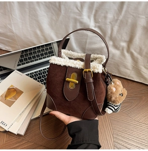 Close-up of brown suede bucket bag with white fleece trim and gold clasp detail
