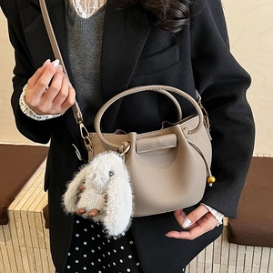 Detail view of taupe leather bucket bag with litchi grain and cute white bunny charm