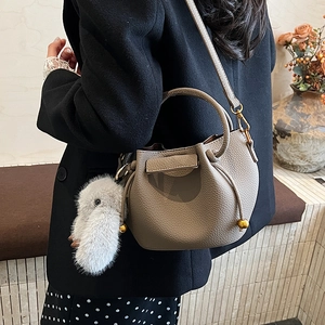 Close-up of elephant gray lychee leather bucket bag with fur charm and gold beads