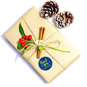 Deep blue round thank you sticker on brown kraft gift box with pine cones and twine