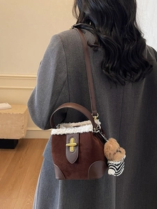 Brown suede bucket bag with white fleece trim and a cute bear charm shown on a model