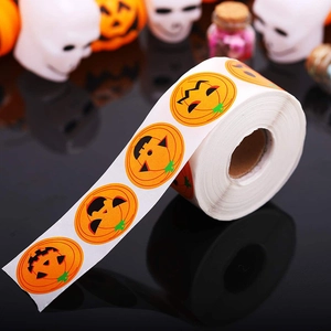 Roll of vibrant orange pumpkin face stickers for Halloween decor on a dark background