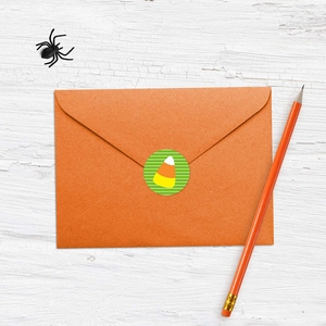 Detail of candy corn sticker sealing an orange envelope on a white wooden table