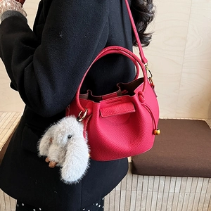Macro detail of magenta litchi leather bucket bag with cute plush bunny charm detail