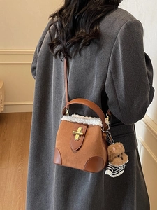 Brown suede bucket bag with shearling trim and cute bear charm shown on model back