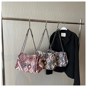 Detailed view of three woven crossbody bags with geometric patterns and chain straps