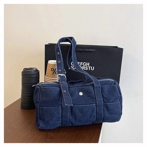 Detail view of navy blue denim Boston bag featuring silver hardware on a wooden table