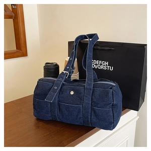 Detail of large navy blue denim tote bag featuring side metal snaps and sturdy fabric straps