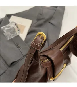 Detail of adjustable shoulder strap and matte gold buckle on brown oversized hobo bag