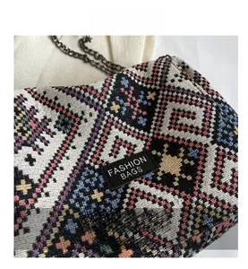 Detailed close-up of woven geometric ethnic patterns and leather logo on the tote bag