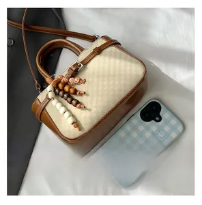 Top view of retro beige woven handbag with brown leather trim and beaded charm detail