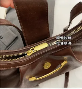 Detail view of smooth golden zipper and curved metal trim on dark brown leather bag