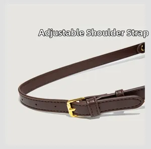 Detail of deep brown leather bag adjustable strap with gold-tone metal buckle