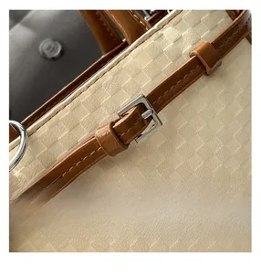 Detail of cream woven texture and brown leather strap with silver buckle on handbag