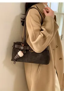 Detail of dark brown suede shoulder bag with a cute plush ice cream pendant on a coat