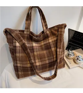 Détail de la large bandoulière et de la texture en laine à carreaux marron du sac cabas