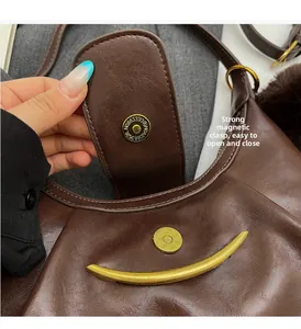 Detail of magnetic snap closure and metal zipper on dark brown pleated hobo bag