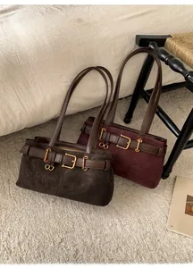 Detail of dark brown and burgundy suede baguette bags with vintage buckle straps