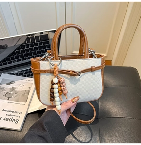 Detail of checkered mini tote bag featuring wood bead charm and brown leather handles