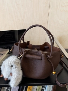 Dark brown leather bucket bag with plush rabbit charm and adjustable shoulder strap