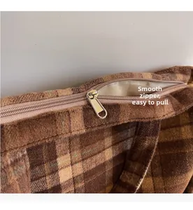 Gros plan d'une fermeture éclair dorée sur un sac cabas à carreaux marron en tissu doux