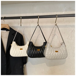 Three quilted shoulder bags in white, black and beige hanging on metal hooks