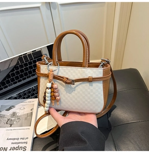 Detail of white checkered patterned handbag with brown leather strap and wooden beads