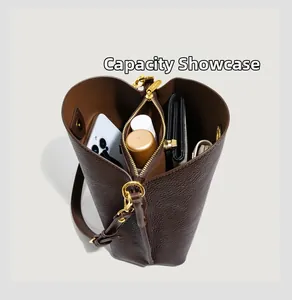 Detail of dark brown leather bucket bag interior showing spacious central zip compartment