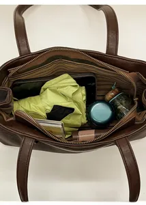 Top view of spacious interior of brown baguette bag with stripe lining and daily essentials