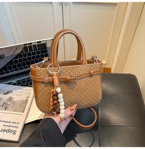 Detail of a brown checkered leather handbag with a beaded tassel in a chic lifestyle setting