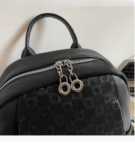 Close-up of smooth silver zippers on black lychee leather backpack with grid embossing