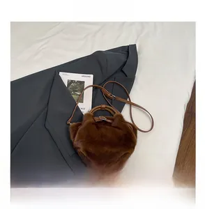 Detalle de bolso de peluche marrón con textura de piel sintética y hebilla metálica