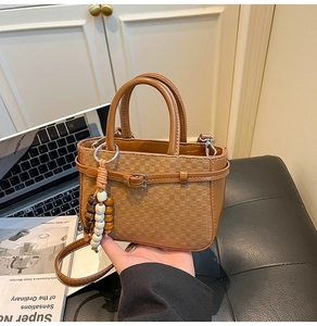 Detail of caramel leather handbag featuring woven texture and wooden bead charm accessory
