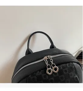 Detail of black backpack featuring silver double zippers and textured checkerboard pattern