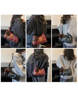 Detail view of large-capacity pleated hobo bag with gold buckle and plush pendant charm