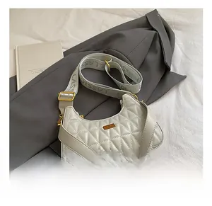 Detail view of crescent shoulder bag with diamond quilting and wide jacquard strap