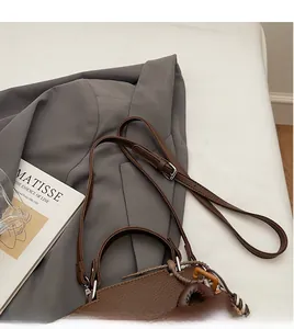 Detail view of brown pebbled leather handbag with adjustable strap and woven accents