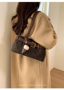 Detail of dark brown retro baguette bag with decorative buckle and plush charm