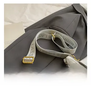 Detail of adjustable beige fabric shoulder strap with gold metal buckle on quilted bag