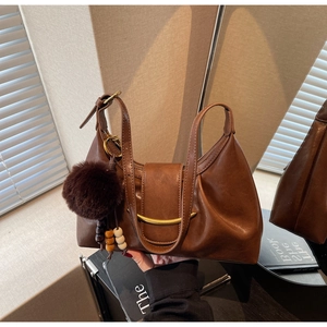 Detailed shot of a vintage brown leather shoulder bag with a metal arc and furry charm