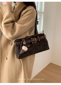 Detail of retro dark brown baguette bag with plush ice cream charm on beige coat
