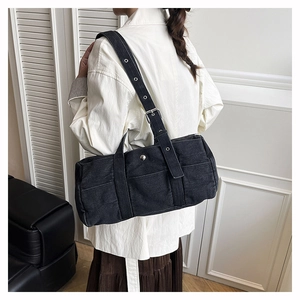 Detail of black denim tote bag with adjustable wide strap and silver metal grommets