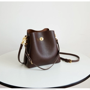 Close-up of deep brown pebbled leather bucket bag featuring a classic gold twist-lock