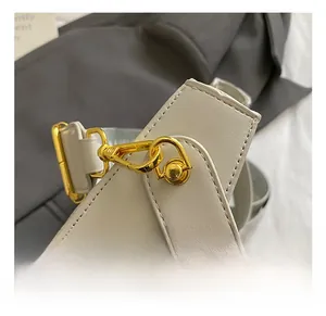 Detail of durable gold metal hook and fine stitching on a light grey leather shoulder strap