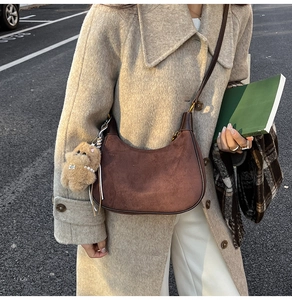 Detail of vintage brown suede crescent bag featuring leather strap and bear charm accessory