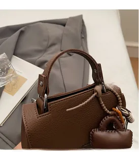 Detail of dark brown lychee grain leather handbag with silver studs and logo charm