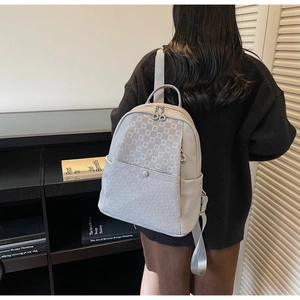 Detail view of light grey women's backpack with geometric square embossing and twin zippers