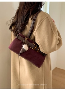 Close-up of burgundy suede baguette bag with leather strap and plush ice cream charm