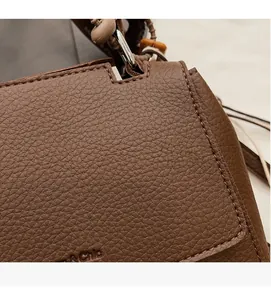 Macro shot of brown pebble-grain leather bag with detailed stitching and beaded strap
