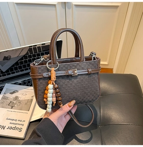 Detail of brown checkered woven mini bag with beaded tassel and metal buckle decor